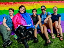 Photo of students on the lawn with a rainbow flag