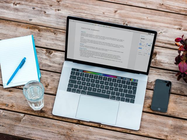 Laptop, phone, and notepad sitting on a desktop