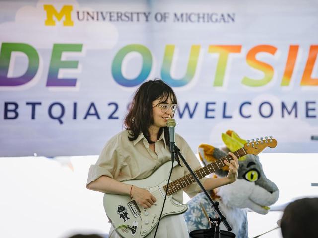 A performer at Pride Outside, playing the guitar and singing